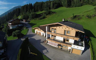Landschaftsaufnahme des Ferienhauses Zeller am Stummerberg in grüner Umgebung mit Bergen im Hintergrund.