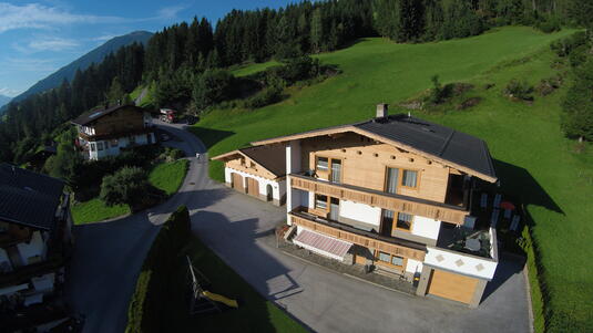 Landschaftsaufnahme des Ferienhauses Zeller am Stummerberg in grüner Umgebung mit Bergen im Hintergrund.
