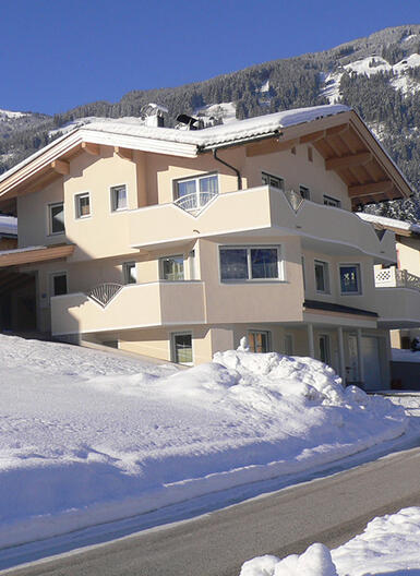 Winterliche Landschaft mit dem modernen Haus in Fügen, umgeben von Schnee und Tannenbäumen.