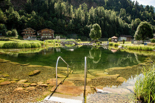 Freibad in Stumm mit umliegender Natur. Klare Reflexionen im Wasser sichtbar.
