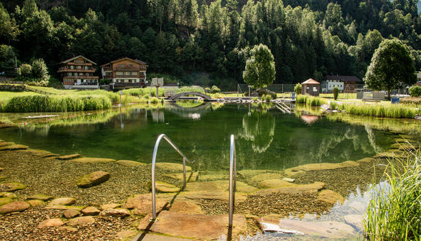 Freibad in Stumm mit umliegender Natur. Klare Reflexionen im Wasser sichtbar.