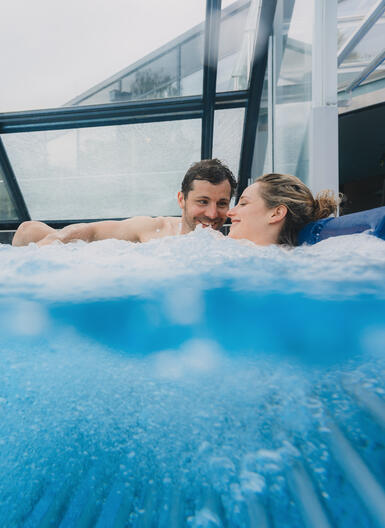 Paar entspannt im Wasser im Aussenbereich der Therme Fügen.