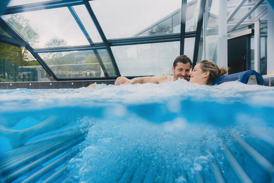 Paar entspannt im Wasser im Aussenbereich der Therme Fügen.