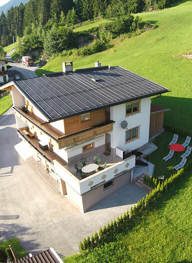 Luftaufnahme des Ferienhaus Zeller am Stummerberg, umgeben von Wiesen und Bäumen, mit Garten und Terrasse.