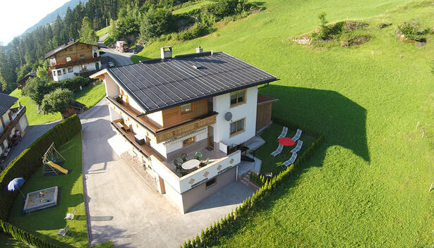Luftaufnahme des Ferienhaus Zeller am Stummerberg, umgeben von Wiesen und Bäumen, mit Garten und Terrasse.
