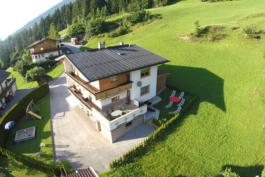 Luftaufnahme des Ferienhaus Zeller am Stummerberg, umgeben von Wiesen und Bäumen, mit Garten und Terrasse.